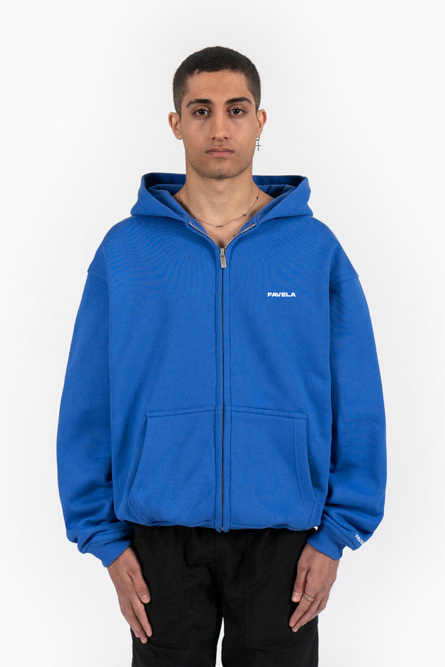 Model trägt royal blue frontzip hoodie mit oversized fit und favela logo auf der brust