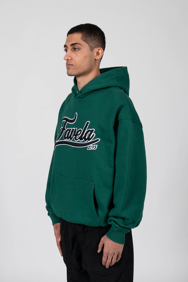 Model wears forest green snap button hoodie by Favela Clothing